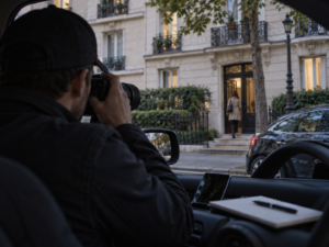 Enquêteur photographiant depuis un véhicule une personne entrant dans un immeuble parisien